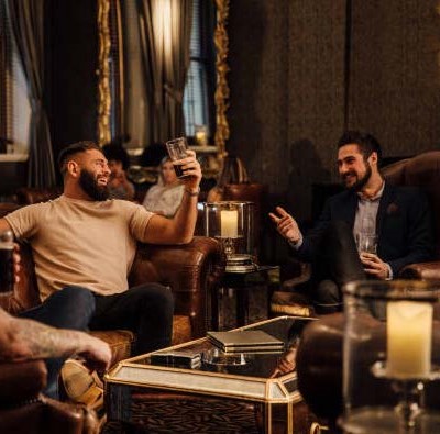 Two men drinking cocktails and talking in bar lounge.