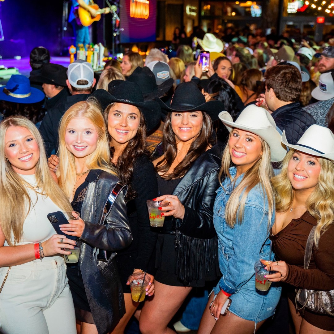 Six women in cowboy hats with drinks at PBR Nashville.